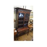 A bookcase on stand, the dentil and Greek key cornice above a pair of bar glazed doors,