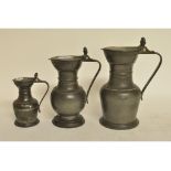 A set of three graduated pewter measures, with double acorn finials,