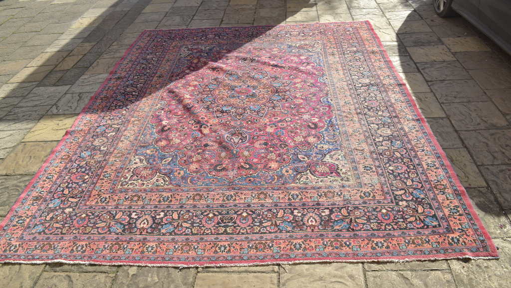 A Persian carpet, decorated a central floral medallion on a pink ground, within a multi border,