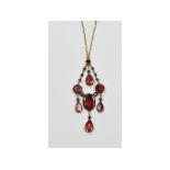 A yellow coloured metal and garnet pendant,