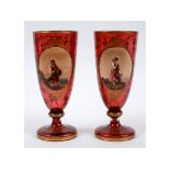A pair of Bohemian ruby glass goblets, each decorated a painted plaque with a child in a landscape,