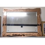 An Art Deco mirror, the mirrored frame decorated stylised berries and foliage,