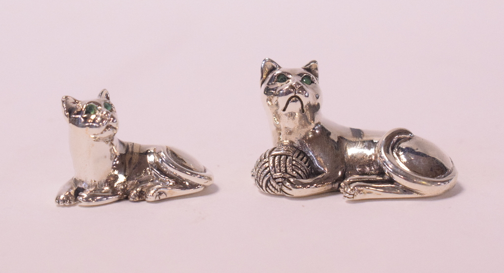A miniature silver cat, with emerald set eyes, 2 cm high,