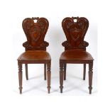 A pair of early 19th century mahogany hall chairs, with shaped backs and tapering reeded front legs,