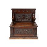 A late 19th century carved walnut box settle, decorated mythical beasts, flowers and foliage,