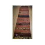 A Persian flatweave runner, decorated stripped motifs on a red ground,