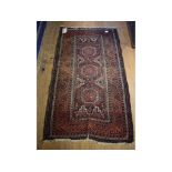 A Baluch rug, decorated three medallions on a brown ground, within a multi border,