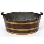 A George III style mahogany oval wine cooler, bound in brass, with a liner,