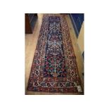 A Persian runner, decorated stylised flowers and foliage on a blue ground, within a multi border,