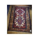 A Persian rug, decorated two stylised flowerheads on a red ground, within a multi border,