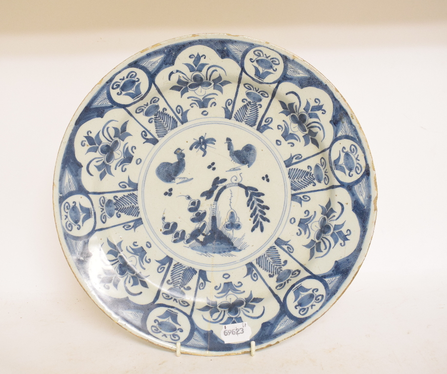 A Delft plate, decorated chickens, flowers and foliage, chipped and cracked, 34 cm diameter,