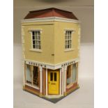An end of terrace corner doll's house, comprising a flat over a shop,