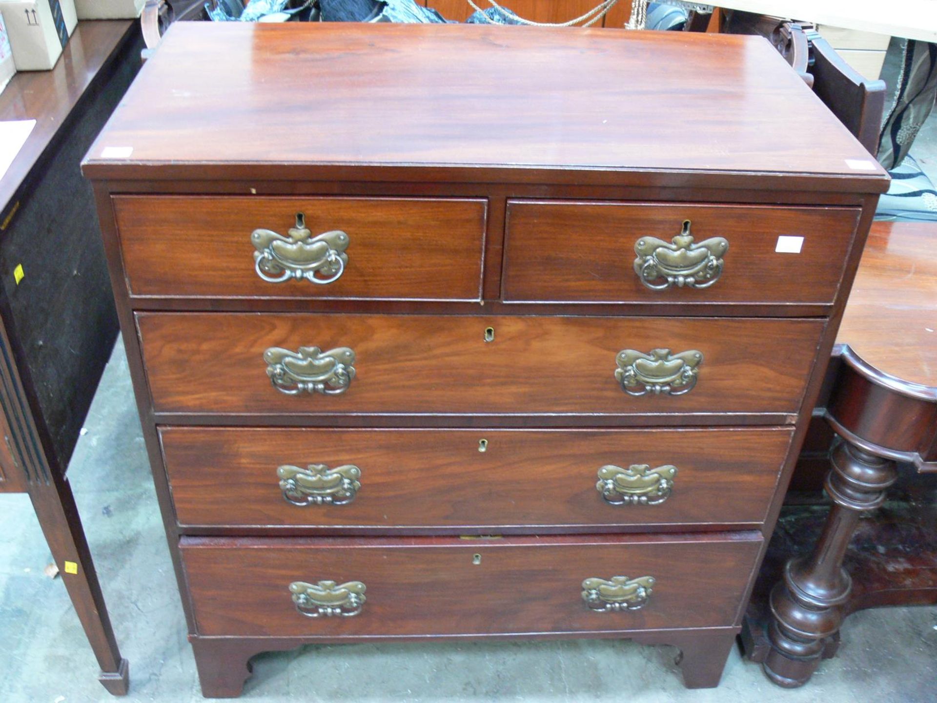 A chest of five drawers with metal drop handles on bracket feet (H101cm W92cm D50cm) (est £70-£90)