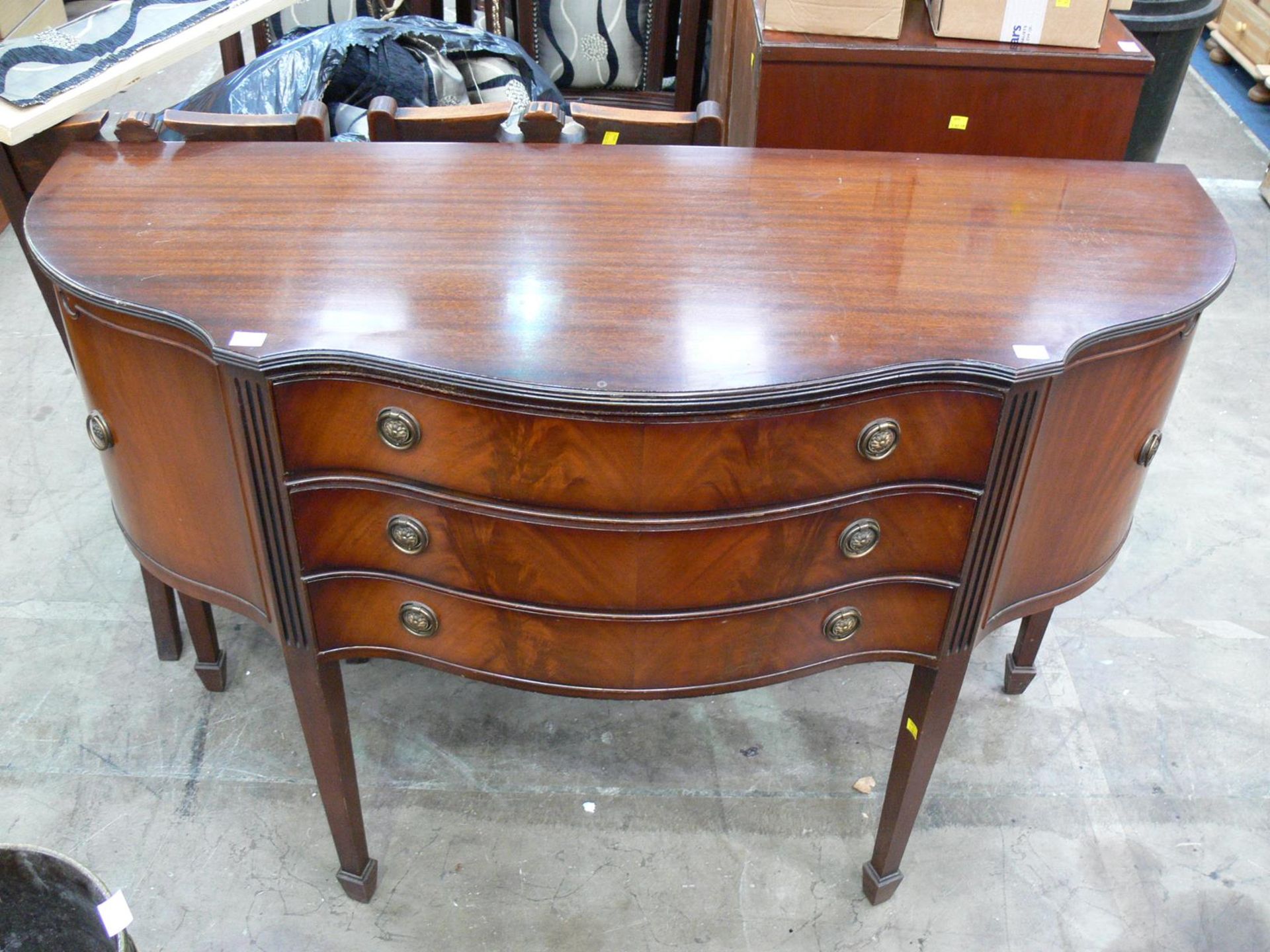 A bow fronted secretaire with three drawers and cupboards to each side, the whole on tapering