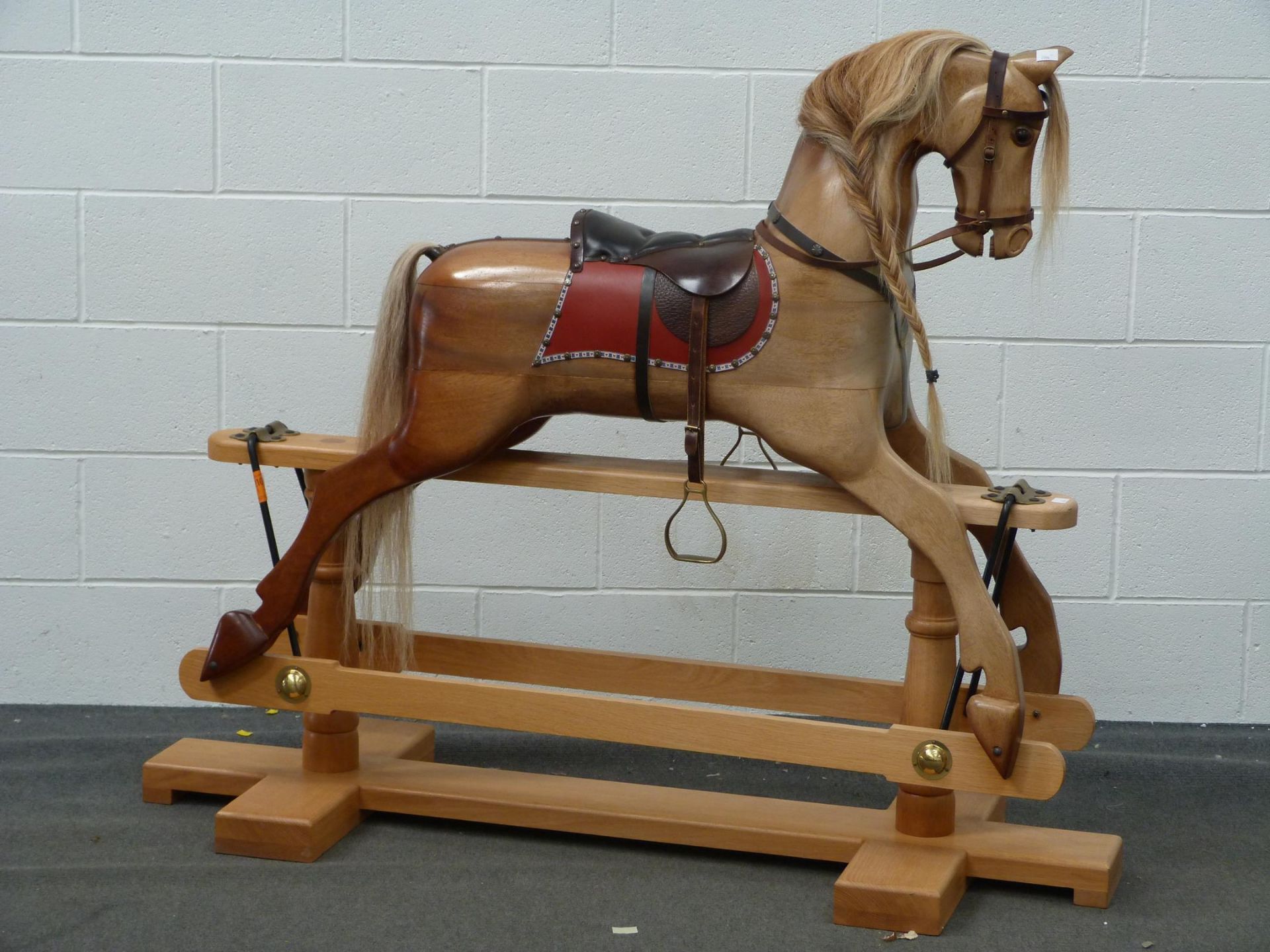 A Large Wooden Rocking horse with horse hair mane and tail with leather saddle, halter and brass