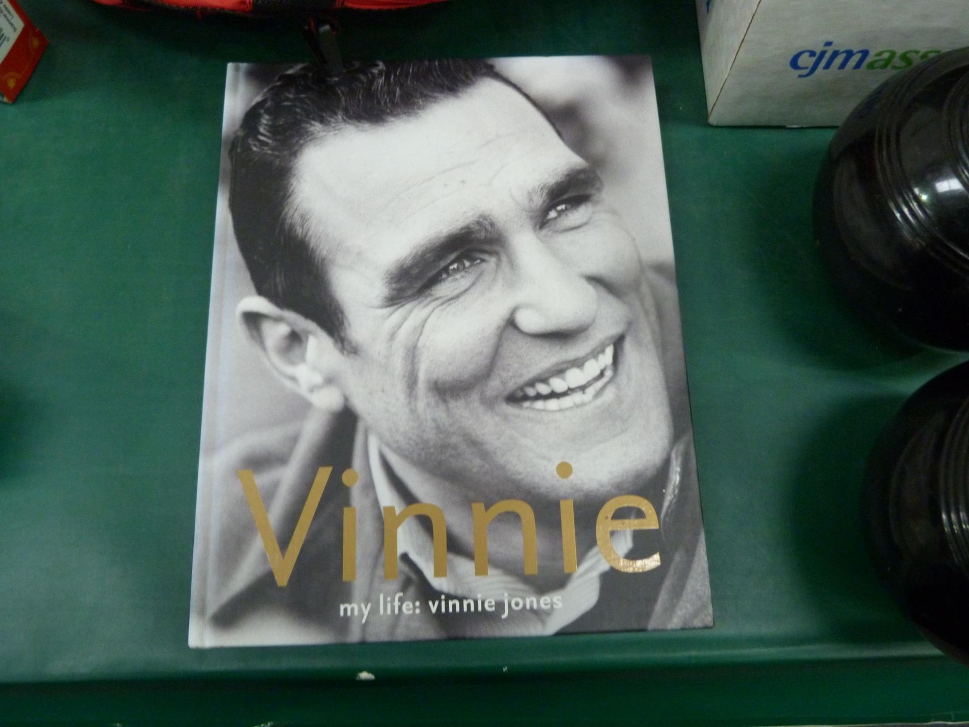 An assortment of items to include a signed Vinnie Jones Autobiography, a Cunard Queen Elizabeth Bag,