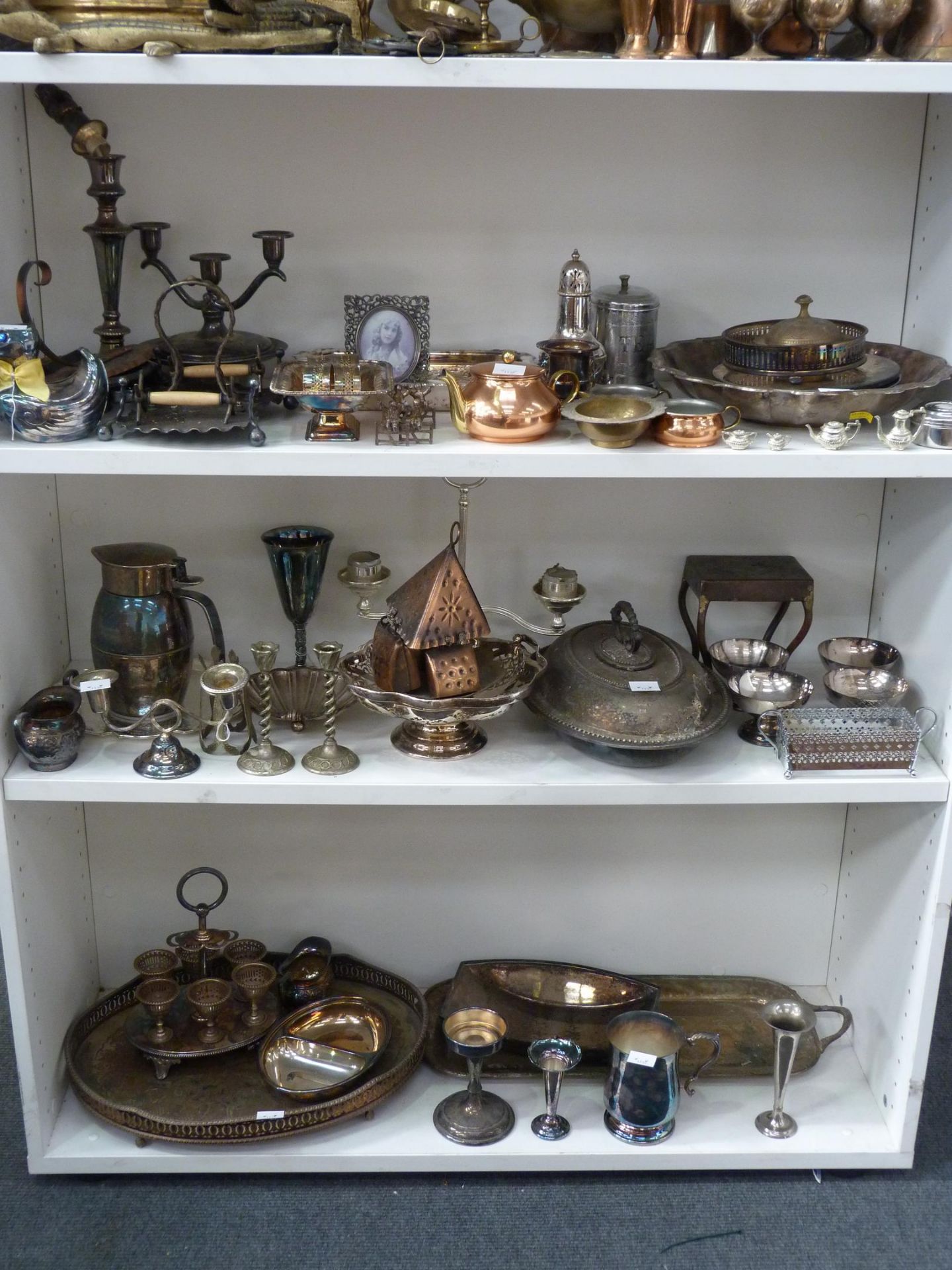 Three shelves to contain a selection of Stainless Steel, Silver Plated items to include Candlesticks