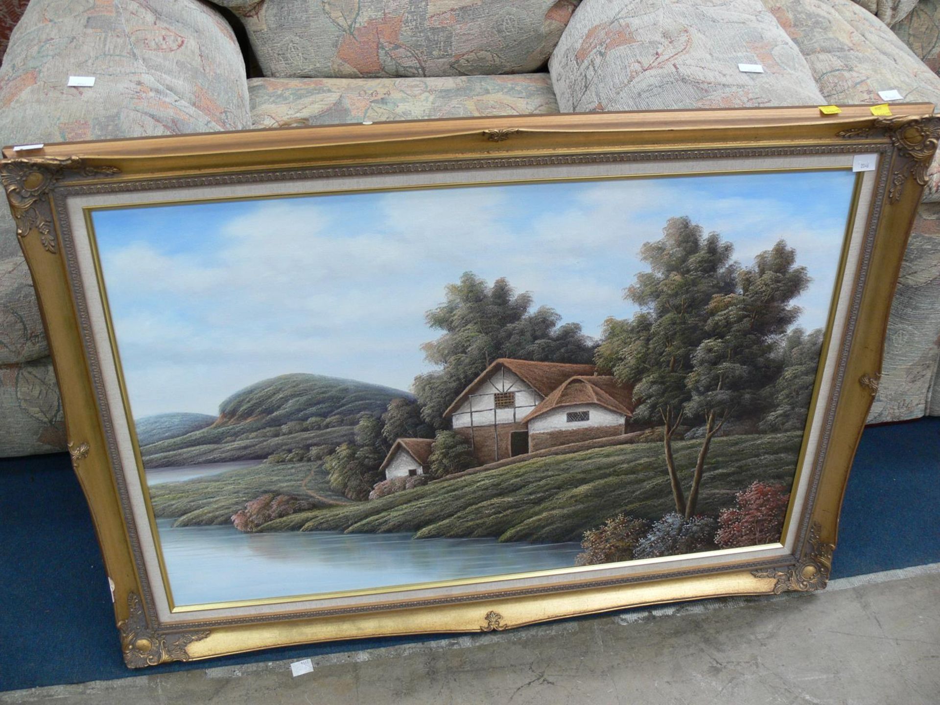 A Large Painting of a Cottage on a Riverbank (est, £30-£50)