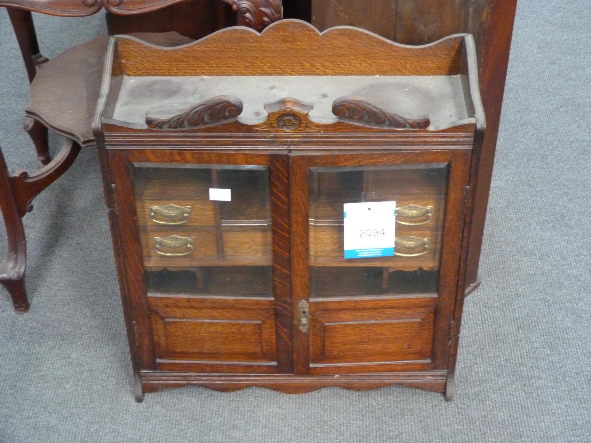 An Edwardian Smokers Oak Cabinet with two glazed doors enclosing a partly fitted interior of