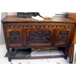 An oak sideboard with two long drawers above three cupboard doors, each carved with flowers & fruit,