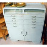 A 1950's dentist's cabinet, a pair of sliding glass doors above ten graduated drawers, with