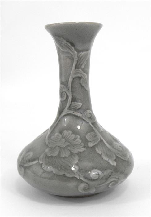 A celadon glazed vase decorated in slight relief with scrolling flowers 14cm high