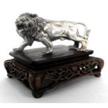 A silver coloured metal lion mounted on a chinese hardwood stand 16cm x 14cm