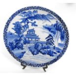 A Japanese blue and white charger, decorated a river scene 40cm diameter