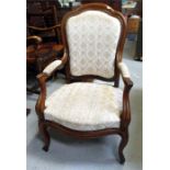 A Victorian carved walnut upholstered open armchair with cabriole front legs.