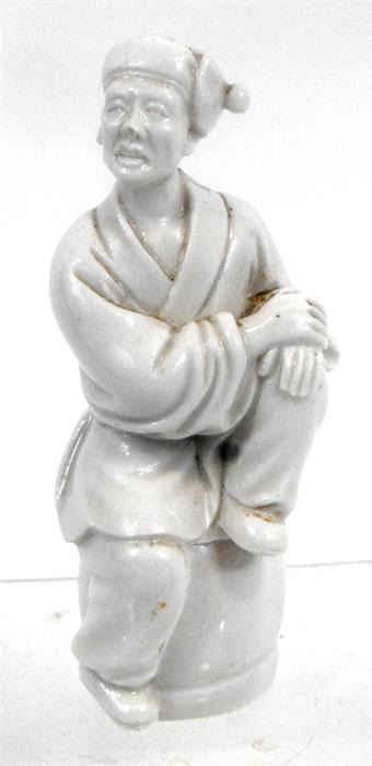 A Chinese Blanc De Chine figure of a man sat on a barrel, 11.5cm high.