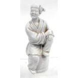 A Chinese Blanc De Chine figure of a man sat on a barrel, 11.5cm high.