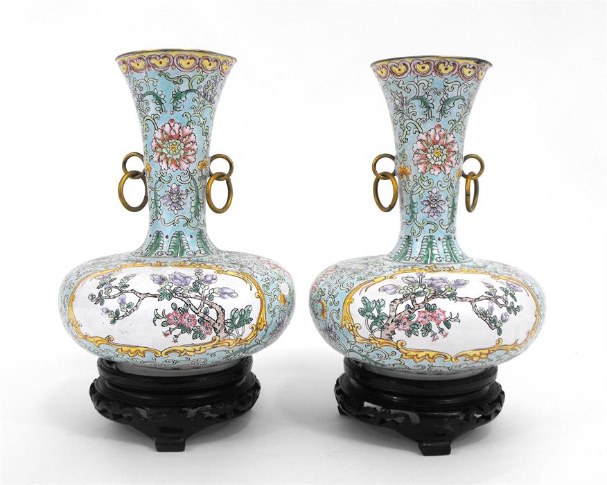 A pair of Chinese enamel vases on stands, decorated with flowers on a pale green ground, 20cm high.