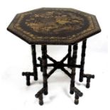 An early 19thC Chinese trade octagonal lacquer table on folding faux bamboo stand, decorated