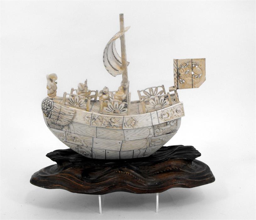 An early 20thC Japanese bone boat with five figures on a carved wooden base (some losses) 24cm x