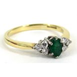 An 18 carat gold diamond and emerald ring, the oval emerald flanked by six diamonds