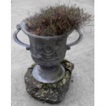 A lead two handled garden urn on a stone plinth 46cm high