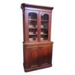 A Victorian mahogany bookcase cupboard, having a pair of glazed doors enclosing two shelves with a