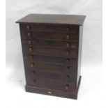 A stained pine collectors cabinet with eight long graduated drawers and makers label "A W Gamage"