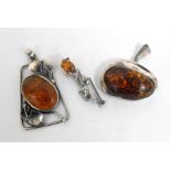 A silver and amber pendent, another similar, and a silver and amber brooch (3)