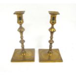 A pair of brass candlesticks on square dished bases 23cm high