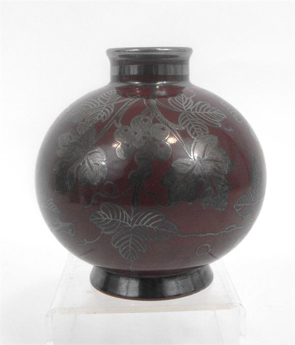 A Richard Ginori bulbous vase with grape and vine silver overlay decoration on a deep red ground,