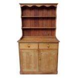 A Victorian pine dresser, the shelved plate rack above two short drawers with cupboards beneath