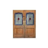 A pair of pine doors with stained glass panels and three stained glass windows.
