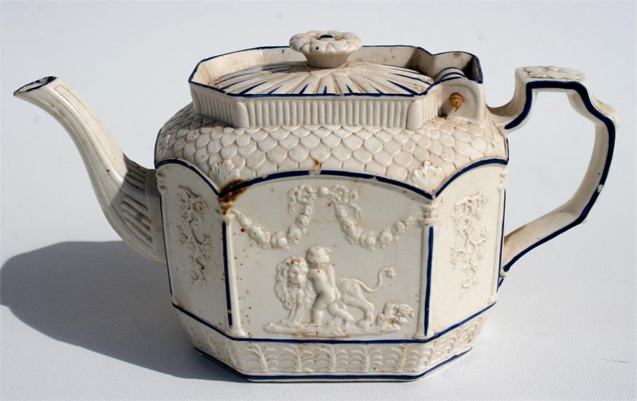 A 19th Century Parian glazed teapot with blue decoration and cherub embossed panels, 14.5cm high.