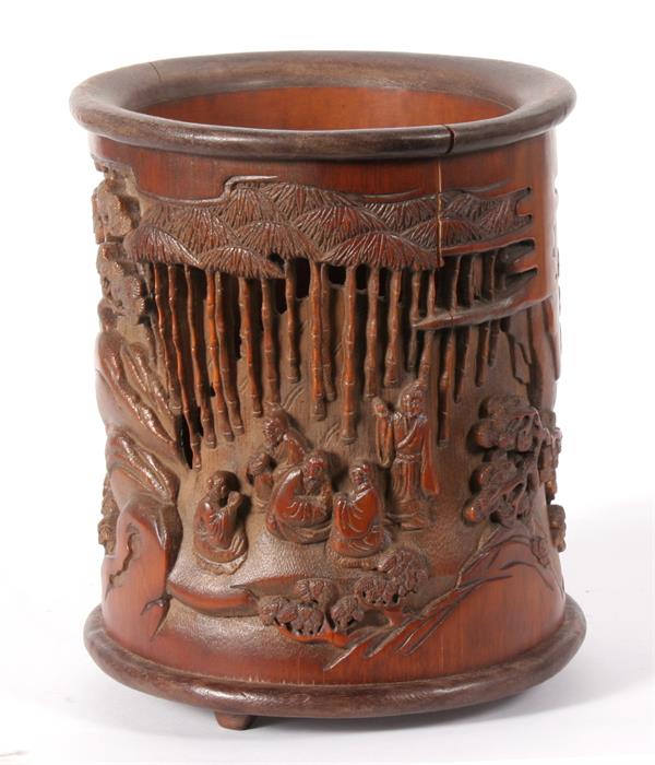 A Chinese pierced and deeply carved brush pot, depicting figures sat around tables with prunus and