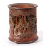 A Chinese pierced and deeply carved brush pot, depicting figures sat around tables with prunus and