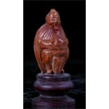A Chinese carved heidao nut in the form of a seated man with a fish in a basket 4.5cm high
