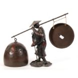 A late 19th century Chinese bronzed figure of a peasant carrying a gong and a bell, 25cm high.