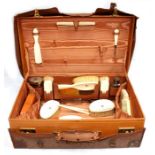 A Gentleman's fitted leather travelling case with canvas outer, containing silver mounted bottles,