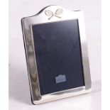 A silver photograph frame surmounted with a pair of crossed tennis rackets, London 1999, 13.5cm x